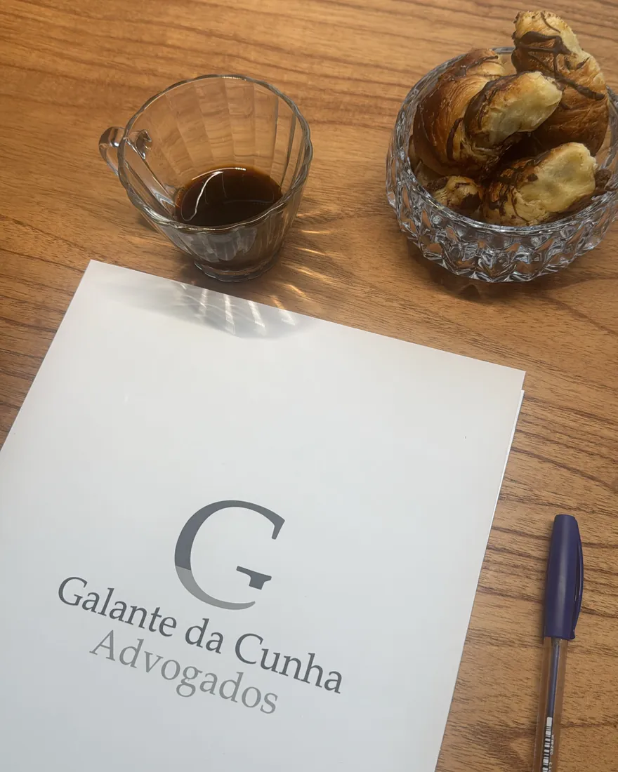 Café servido sobre a mesa, ao lado de papel com a marca do escritório